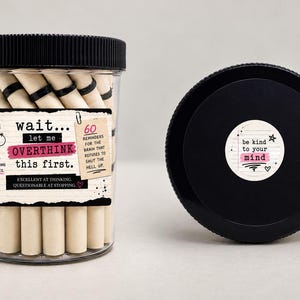 May include: A clear plastic jar with a black lid containing beige paper rolls. The label reads: wait... let me OVERTHINK this first. It's not thinking too much. It's thinking in circles. 60 reminders for the brain that refuses to shut the hell up.