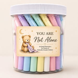 May include: A clear plastic jar with a white lid filled with pastel-colored paper scrolls. The label features a brown teddy bear holding a purple blanket, a crescent moon, stars, and the text: YOU ARE Not Alone 60 Gentle Reminders for Parents.