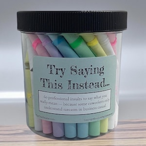 May include: A transparent plastic jar with a black lid, containing numerous colourful rolled-up papers. The label reads "Try Saying This Instead..." and lists 60 professional insults. TheTiredNurse.com is also printed on the label.