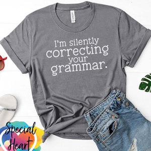 May include: Grey t-shirt with white text that reads "I'm silently correcting your grammar."
