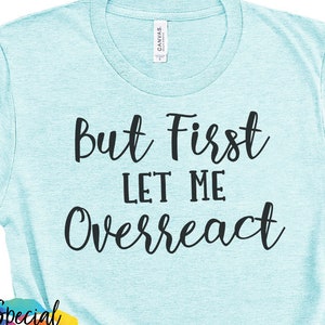 Puede incluir: Una camiseta azul claro con el texto "But First Let Me Overreact" en letras negras.