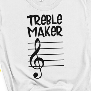 May include: White t-shirt with black text that reads "Treble Maker" and a treble clef symbol on a musical staff.