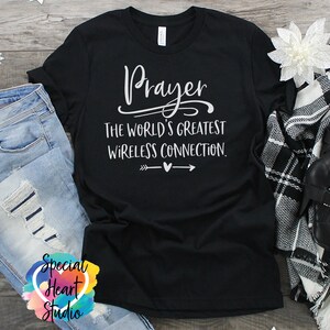 May include: Black t-shirt with white text that reads "Prayer The World's Greatest Wireless Connection."  The text is surrounded by a white heart and arrows.