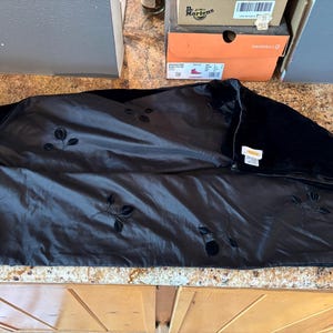 May include: A black velvet garment with a satin lining. The lining features embroidered leaf designs. The garment is spread out on a countertop. A tag with the brand name "Talbots" is visible.