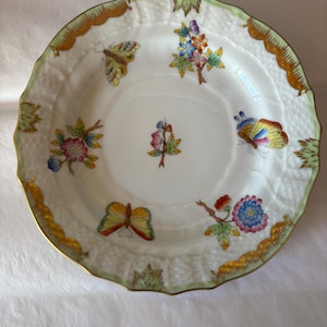 May include: White porcelain decorative plate with a scalloped edge, featuring colorful butterflies and floral designs. The rim has a gold and green trim. A beautiful piece for display or serving.