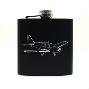 May include: Black stainless steel hip flask with a silver cap and a white outline of a small airplane engraved on the front.