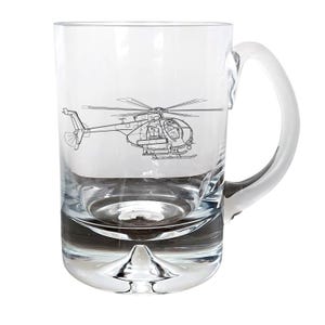 May include: A clear glass beer mug with a helicopter design etched on the front. The helicopter is a single-rotor aircraft with a long fuselage and a tail boom.