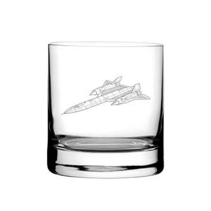 May include: A clear, lowball glass featuring a detailed line drawing of a SR-71 Blackbird aircraft. The glass has a thick base and a cylindrical shape, suitable for whiskey or other beverages. The aircraft illustration is centered on the glass.