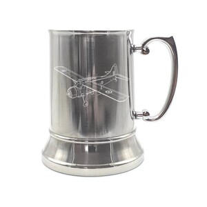May include: A cylindrical stainless steel beer tankard featuring a laser-etched line drawing of a vintage propeller aircraft on its front surface. The tankard has a polished metallic finish, a wide base, and a sturdy, curved handle attached to the side.