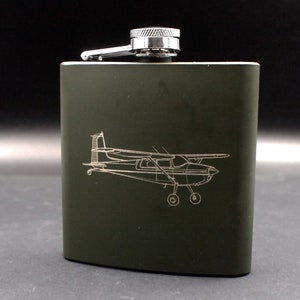 May include: A green metal flask with a silver cap and a laser-etched design of a small airplane.