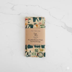 May include: Beeswax food wraps in small, medium, and large sizes. The wraps are beige with a pattern of green, red, and yellow illustrations. A brown paper band around the wraps reads "Green Be Wraps" and "Reusable Beeswax Wraps For Food Storage."