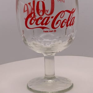 May include: A set of three ceramic mugs with a speckled, cream-colored glaze. Each mug features a different hand-painted floral design in shades of blue, green, and yellow. The mugs have a simple, rounded shape and a comfortable handle.