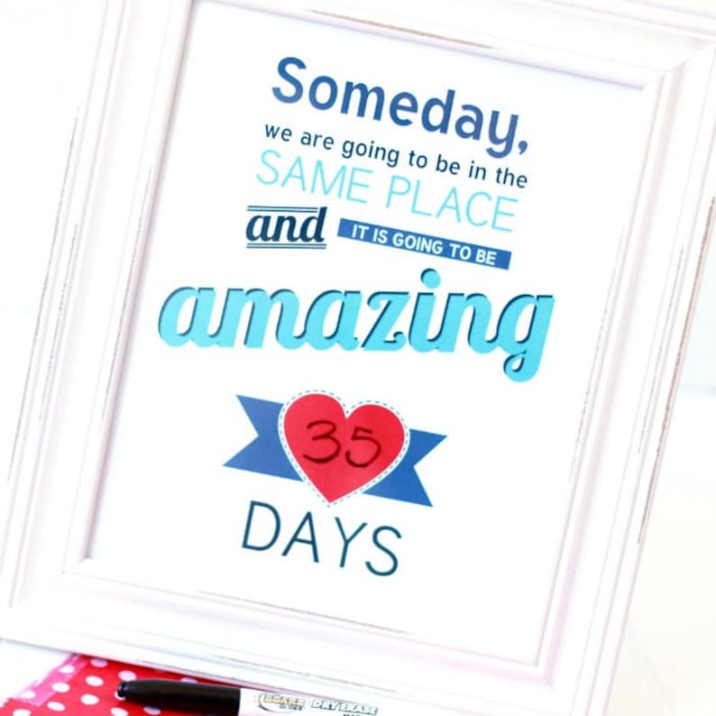 May include: A white framed print with blue and red text that reads "Someday, we are going to be in the SAME PLACE and IT IS GOING TO BE amazing". A red heart with the number 35 inside is below the text, and the words "DAYS" are below the heart.