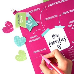 Op de afbeelding: Een roze printbaar werkblad met de titel "Haar favorieten" in een witte pot met een blauw-wit gestreept deksel. Het werkblad heeft secties voor favoriete films, muziekgroepen, dates, restaurants, kleur en lekkernijen. Er zijn ook drie hartvormige stickers in roze, groen en blauw.