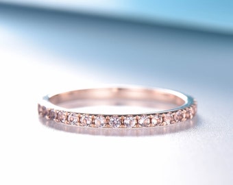 May include: A delicate rose gold band ring with a row of small, clear gemstones.