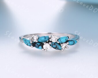 Puede incluir: Un anillo de plata con piedras turquesa y transparentes engastadas en un diseño de hojas.