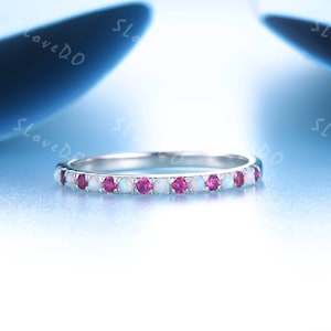 May include: A delicate silver band ring with alternating white opal and pink ruby stones.