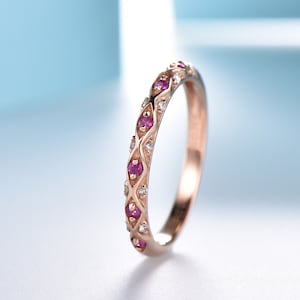 May include: A delicate rose gold band ring with a repeating pattern of small pink gemstones and white diamonds.