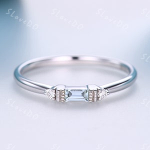 May include: A delicate silver ring with a rectangular aquamarine gemstone and two smaller round diamonds on either side.