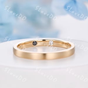 May include: A gold ring featuring a black and a white gemstone. The ring has a smooth, polished finish and a classic design. The gemstones are set in a simple, elegant style. A timeless piece of jewellery.