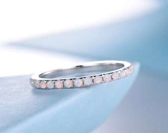 May include: A delicate silver band ring with a row of small white opal gemstones.