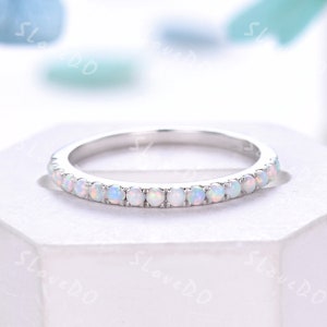 May include: A delicate silver band ring with a row of small white opal stones.