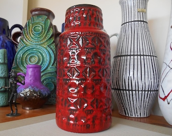 May include: A collection of vintage ceramic vases in various colors and patterns. The vases are arranged on a table with a brown surface. The vases are all different shapes and sizes. The vases are all decorated with intricate designs.