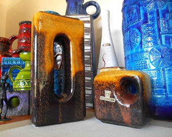 May include: A collection of vintage ceramic vases in various shapes and sizes. The vases feature a mix of colors, including brown, orange, and blue. One vase has a rectangular shape with a large opening. Another has a square shape with a small opening.
