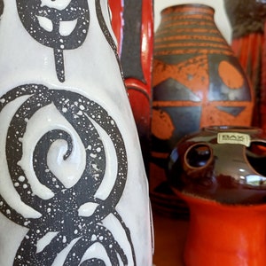 May include: A collection of ceramic vases in various shapes and sizes. The vases feature a range of colors, including white, black, red, and orange. Some vases have abstract patterns and designs, while others have a smooth finish. The collection includes a mushroom-shaped vase.