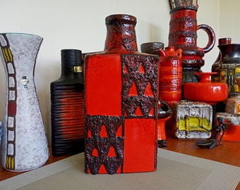 May include: A collection of vintage ceramic vases in various shapes and sizes. The vases are decorated with geometric patterns in shades of red, black, and white. The vases are arranged on a table with a brown surface.