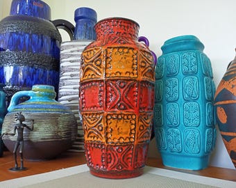 May include: A collection of vintage ceramic vases with geometric patterns. The vases are in various colors, including blue, orange, and turquoise. The vases are arranged on a wooden surface.