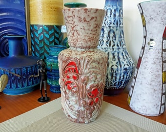 Puede incluir: Un jarrón de cerámica con un esmalte blanco, marrón y rojo. El jarrón tiene una superficie texturizada con diseños florales en relieve y acentos rojos.