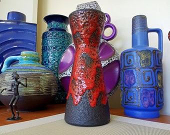 May include: A collection of colorful ceramic vases with geometric patterns. The vases are in shades of blue, green, red, and purple. A small bronze figurine of a person is in the foreground.