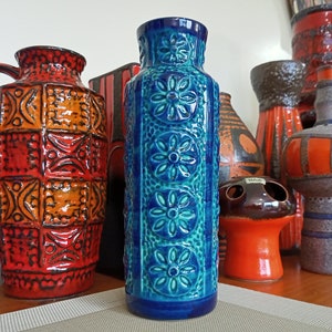 May include: A collection of vintage ceramic vases with geometric and floral patterns. The vases are in shades of blue, orange, and brown.