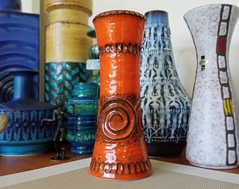 May include: A tall, orange ceramic vase with a swirl design. The vase has a glossy finish and is decorated with brown accents.