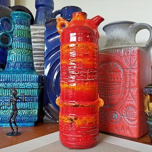 Op de afbeelding: Een verzameling vintage keramische vazen in verschillende kleuren en patronen. De vazen zijn gerangschikt op een tafel met een houten oppervlak. De vazen zijn allemaal in verschillende vormen en maten. De vazen zijn allemaal gemaakt van keramiek en hebben een geglazuurde afwerking.