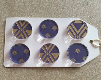 May include: Six round, clear glass magnets with a purple background and gold geometric designs. The magnets are arranged in two rows of three on a white tag.