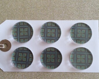 May include: Six round, clear glass magnets with a repeating pattern of green and yellow leaves on a dark blue background.