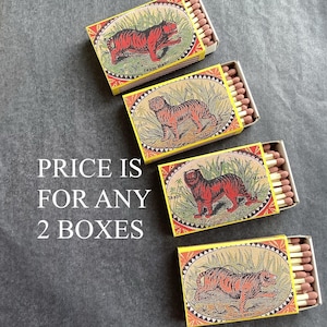 May include: Four matchboxes with a vintage design. Each box displays a red tiger illustration on a yellow background, with the text "TRADE MARK". The boxes are open, showing the matchsticks.