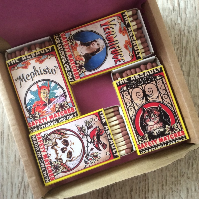 Puede incluir: Un juego de seis cajas de cerillas con ilustraciones coloridas y el texto "The Assault" en cada caja. Las ilustraciones incluyen una calavera, un p&aacute;jaro, un gato, un diablo, una mujer y el texto "Vermifuge".