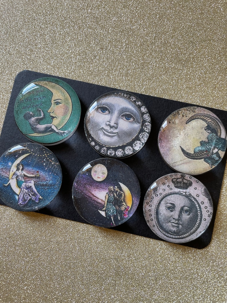 Peut inclure: Six ornements ronds en verre avec des images de lune et d'&eacute;toiles. Les ornements pr&eacute;sentent une vari&eacute;t&eacute; de motifs, notamment une lune croissante avec une femme assise dessus, une pleine lune avec un visage et un couple debout sur une lune croissante. Le texte "Love you to the moon and back" est sur l'un des ornements.