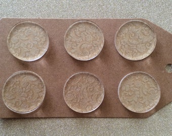 May include: Six round, clear glass magnets with a gold glitter and white paisley pattern.