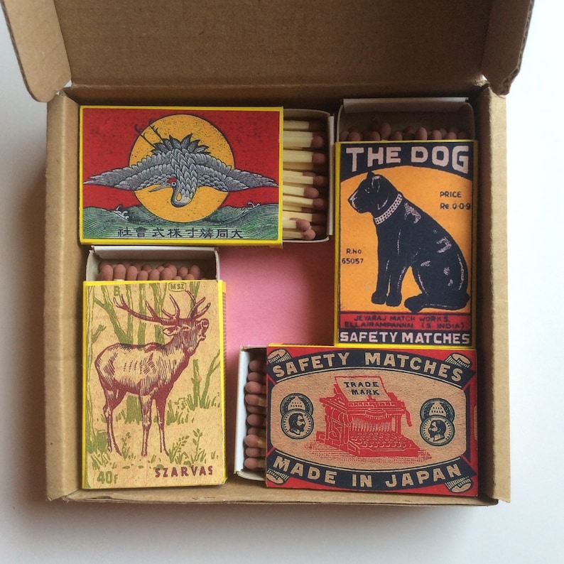 May include: Assortment of matchboxes with various designs. One box features a red, white, and blue butterfly, another a black and white dog, and a third a deer in a forest. The boxes are made in Japan and feature the text "Safety Matches".