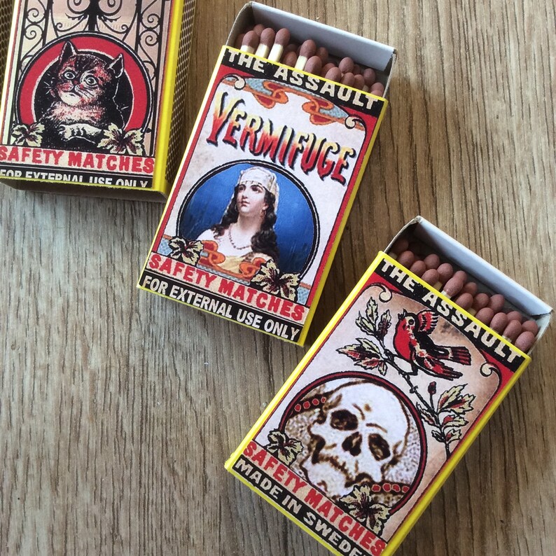 Puede incluir: Tres cajas de cerillas vintage con ilustraciones coloridas y el texto "The Assault", "Vermifuge" y "Safety Matches Made in Sweden".