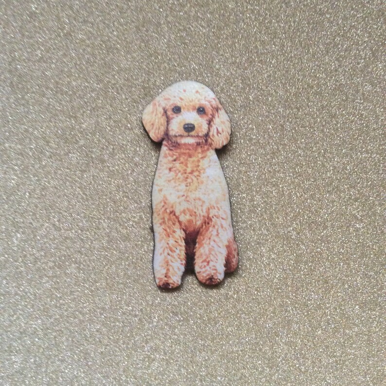 K&ouml;nnte beinhalten: Ein hellbrauner Spielzeugpudel, der mit seinen Pfoten zusammen sitzt. Der Spielzeugpudel ist aus Holz und hat ein gemaltes Bild eines Pudels darauf.