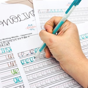 May include: A person's hand writing the letter 'R' on a lined sheet of paper with a turquoise gel pen. The paper has lines for practicing cursive handwriting. The paper has the words 'Uppercase Writing Words' at the top.