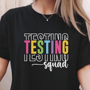 May include: Black t-shirt with the text "Testing Testing Testing Squad" in rainbow colors.