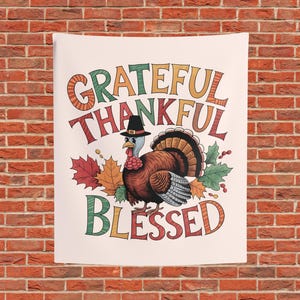 May include: A rectangular wall tapestry featuring a central illustration of a turkey wearing a black pilgrim hat. The text GRATEFUL THANKFUL BLESSED is printed in colorful, stylized lettering. Autumnal maple leaves in red, orange, and green surround the turkey.