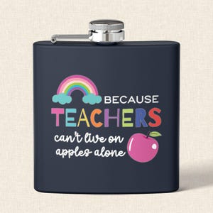 May include: A navy blue flask with a silver cap and hinge. The flask features a rainbow, clouds, and the text "BECAUSE TEACHERS can't live on apples alone" with a pink apple graphic.