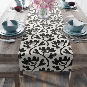 May include: Black and white floral table runner with a modern design. The runner is made of a soft, durable fabric and is perfect for adding a touch of style to any dining table.